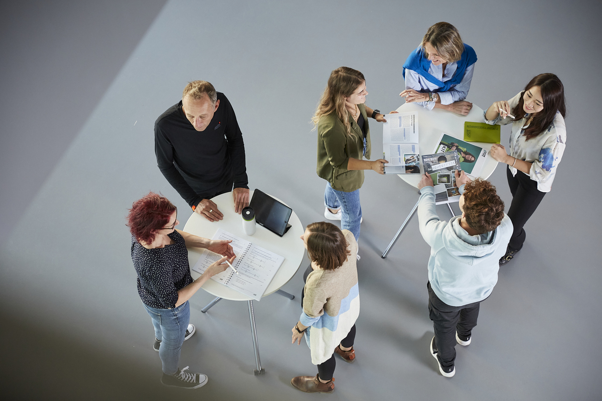 Gruppe von Menschen, die an Stehtischen stehen und sich unterhalten.